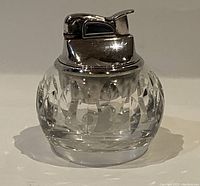 Front view of Waterford crystal butane table lighter showing clear cut crystal body and chrome-tone metal lighter top.