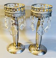 Pair of vintage silver candlestick holders with ornate top rims and hanging clear crystal prisms.