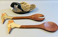Photo of wooden serving spoon and fork with bird head handles, laid flat on a surface