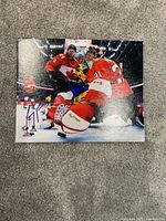 Photo of an autographed Team Canada hockey photo showing players during game action with autograph.