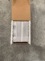 Top view of an open cardboard box filled with NBA basketball trading cards packed tightly standing upright.