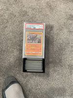 Top view of a black box filled with multiple Pokémon cards and a single PSA graded 2019 Machamp card placed on top, showing the grade and label details clearly.