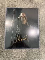 Glossy poster image of Gandalf standing with staff, signed in gold ink in the lower area.