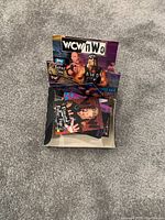 Photo of WCW nWo wrestling trading cards and packs in open box on carpeted floor.