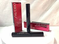 Two black mascara tubes and a red packaging box with Shiseido branding displayed on a white background.