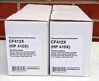 Photo of two white boxes containing CF412X replacement yellow toner cartridges for HP 410X series printers, showing label details.