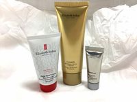 Three tubes of Elizabeth Arden skincare products displayed on a fabric background.