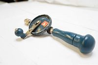 Side angle view of vintage hand crank drill showing wood handle and gear mechanism.