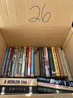Photo showing a box with 21 hardcover books in varied condition and subject matter, arranged side by side with some titles visible on the spines.