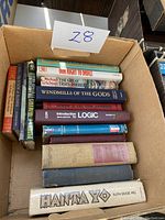 Photo of a cardboard box containing 11 hardcover books of various subject matter including drug rights, logic, mythology, and novels.