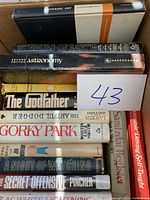 Top view of a box containing ten hardcover books of various subject matter and condition.