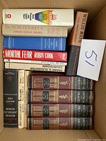 Top view of various hardcover books stacked showing titles and colors.