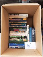 Top view of a box containing 16 hardcover books arranged with spines visible and a note with number 61.