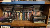 Shelf showing multiple rows of DVD and Blu-ray movie cases, some stacked horizontally on the side.