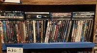Shelf of assorted DVD movies densely packed, visible titles on spines, various genres.