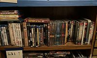 Photo showing DVDs arranged on a wooden shelf, fourth from top, including visible titles such as Victory at Sea, The Agency, and others.