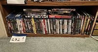 Photo of multiple DVD movie cases on bottom shelf of bookcase, clearly showing rows of assorted titles.