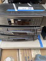 Stacked DVD and two Panasonic VHS players with visible model numbers.