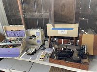 Vintage Singer sewing machine in brown case, Baby Lock electric machine, sewing stool, and sewing accessories on table