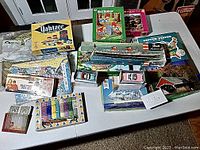 Overview photo showing various vintage games and puzzles including Woody Woodpecker puzzle, Yahtzee box, model ship box, United States map puzzle, and more.