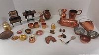 Overview of the full lot including trays of assorted copper and brass miniatures with various kitchenware, furniture, and decorative items.
