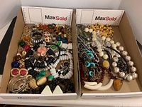 Two trays of assorted large costume jewelry including necklaces, earrings, and bracelets in various colors and styles.