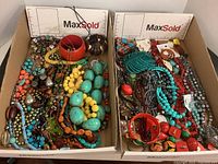 Two boxes filled with assorted colorful beaded jewelry including necklaces and bracelets.