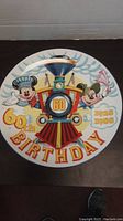 Front view of the commemorative plate showing Mickey and Minnie Mouse with a train and 60th birthday text.