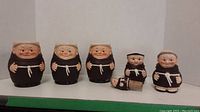 Photo showing all 5 ceramic pieces: three mugs, cream and sugar, and a wine stopper laid in a row.