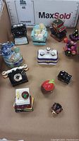 Overview of all 11 small ceramic hinged boxes in various colorful designs placed in a cardboard box.