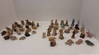 Wide view showing two trays filled with miniature animal figurines in light brown and neutral shades scattered across a white surface.