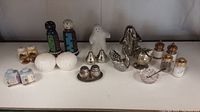 Overview of all 10 salt and pepper shakers made of various materials including metal, ceramic, and glass, showing different patterns and shapes.