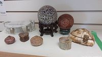 Multiple stone decorative items including carved stone balls, containers, and a marble table shown together