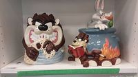 Two Tasmanian Devil cookie jars on shelf, one with Bugs Bunny lid.