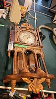 Full view of vintage wooden wall clock showing clock face, carved details, and original winding key.