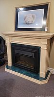 Front view of large electric fireplace showing cream-colored mantel and green marble base with black insert containing faux logs.
