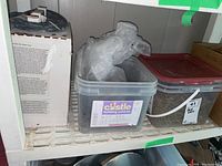 Two bins of screws placed on a shelf, one with a Castle Building Centres label and the other with a red lid.