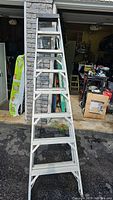 Full length view of Featherlite 8ft aluminum step ladder fully open and standing on driveway with garage in background