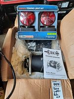 Full view of magnetic towing light kit including two red round lights, blue frame, and Power 110 Mite AC generator with instructions in a box.