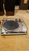 Front angle view of the Technics SL-Q2 turntable with closed dust cover on carpeted floor.