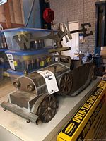 Top-side angled view showing vintage car shaped weather vane and directional letters with part of surrounding environment.