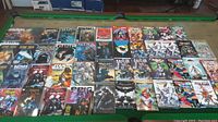 Wide view of first set of comic books arranged on a pool table, featuring titles such as Batman, Star Trek, Shield and Spider-Man.