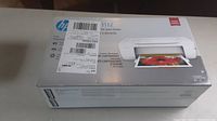 Box front showing HP DeskJet 1112 branding, printer image printing color photo, stickers affixed to box.