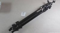 Folded Manfrotto tripod with leg clamps and head visible.