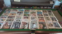Wide view of 44 Rolling Stone magazine issues laid out on green felt pool table showing assorted covers from 1973-1976.