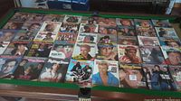Overhead photo displaying 45 Rolling Stone magazine issues arranged in seven rows on a green pool table, featuring various cover images of notable 1980s musicians and celebrities.