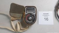 Weston Master IV light meter inside worn original leather case with strap, showing meter face with dial and markings.