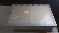 Rectangular white metal X-Ray box from WOLF, closed top surface with clamps and slight wear visible.