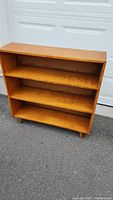 Full view of the 3 shelf wooden bookcase showing shape, color, and condition.