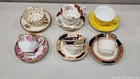Six Royal Albert cups and saucers arranged on a surface, varying patterns and colors, appear intact